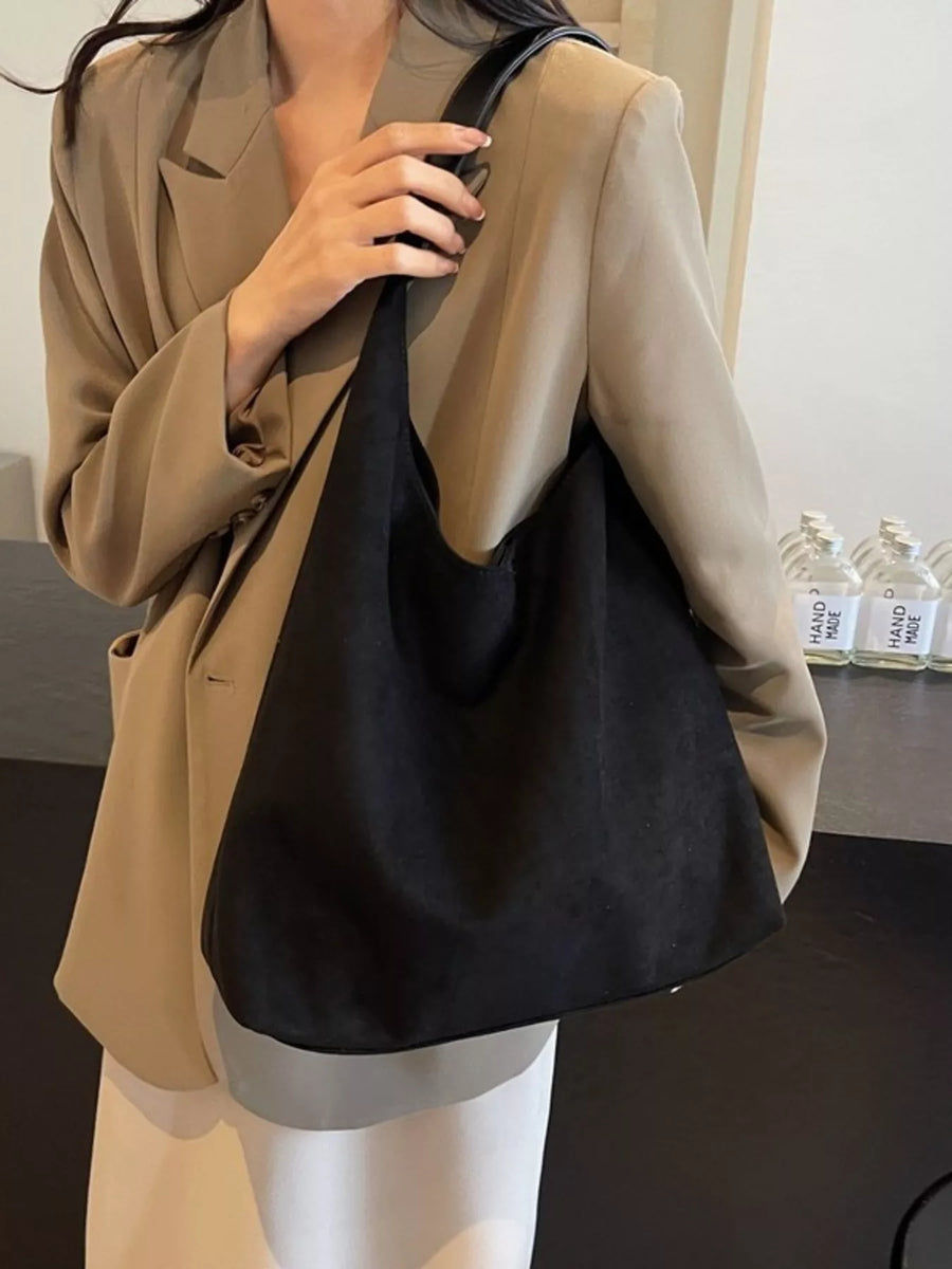 Black suede hobo bag with a slouchy silhouette and single strap.