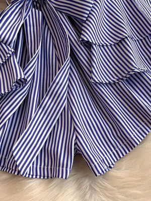 Blue and white striped romper with ruffles and a bow detail.