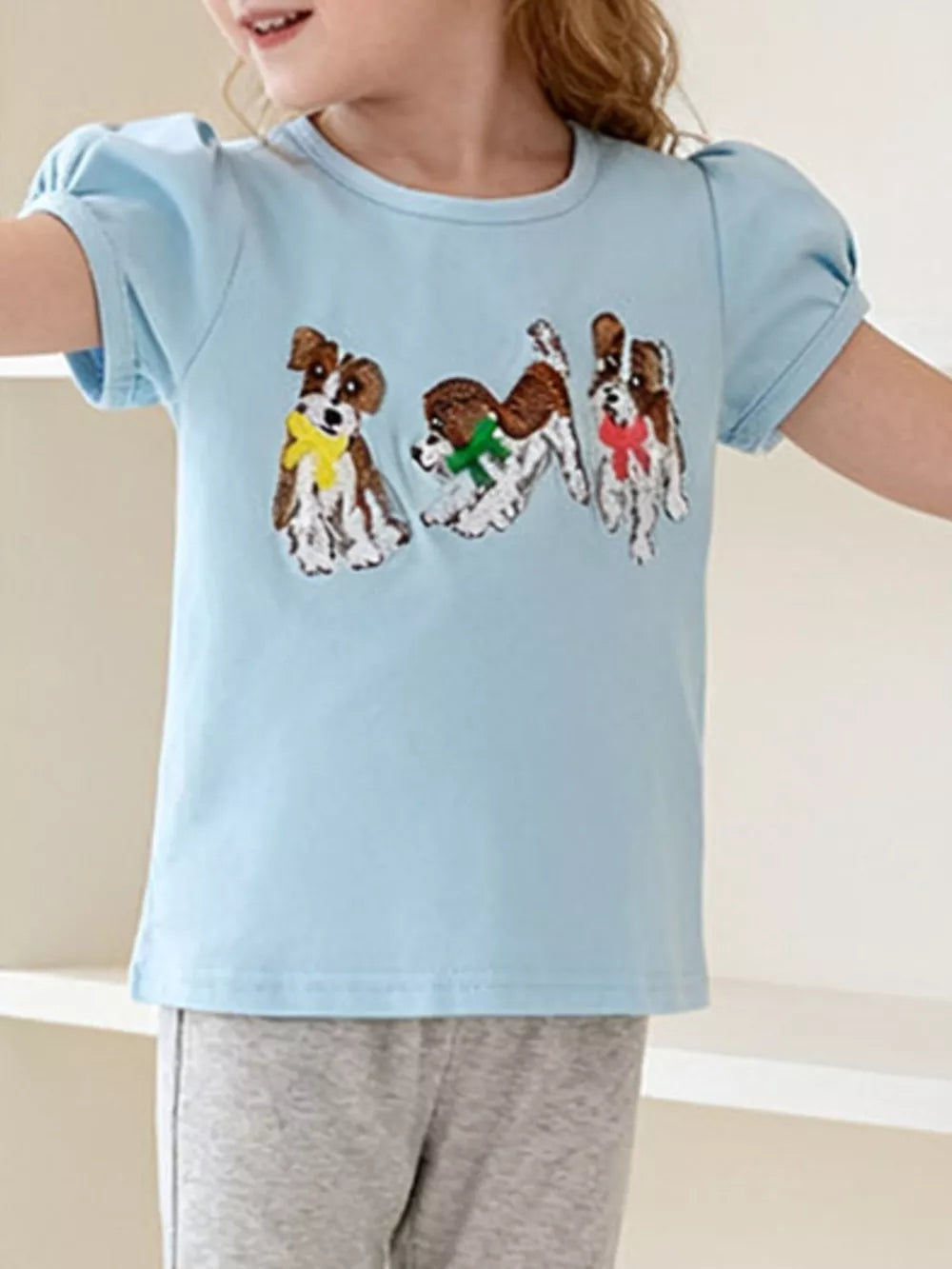 Light blue cotton blend toddler t-shirt with three embroidered puppies wearing colorful scarves and puff sleeves.