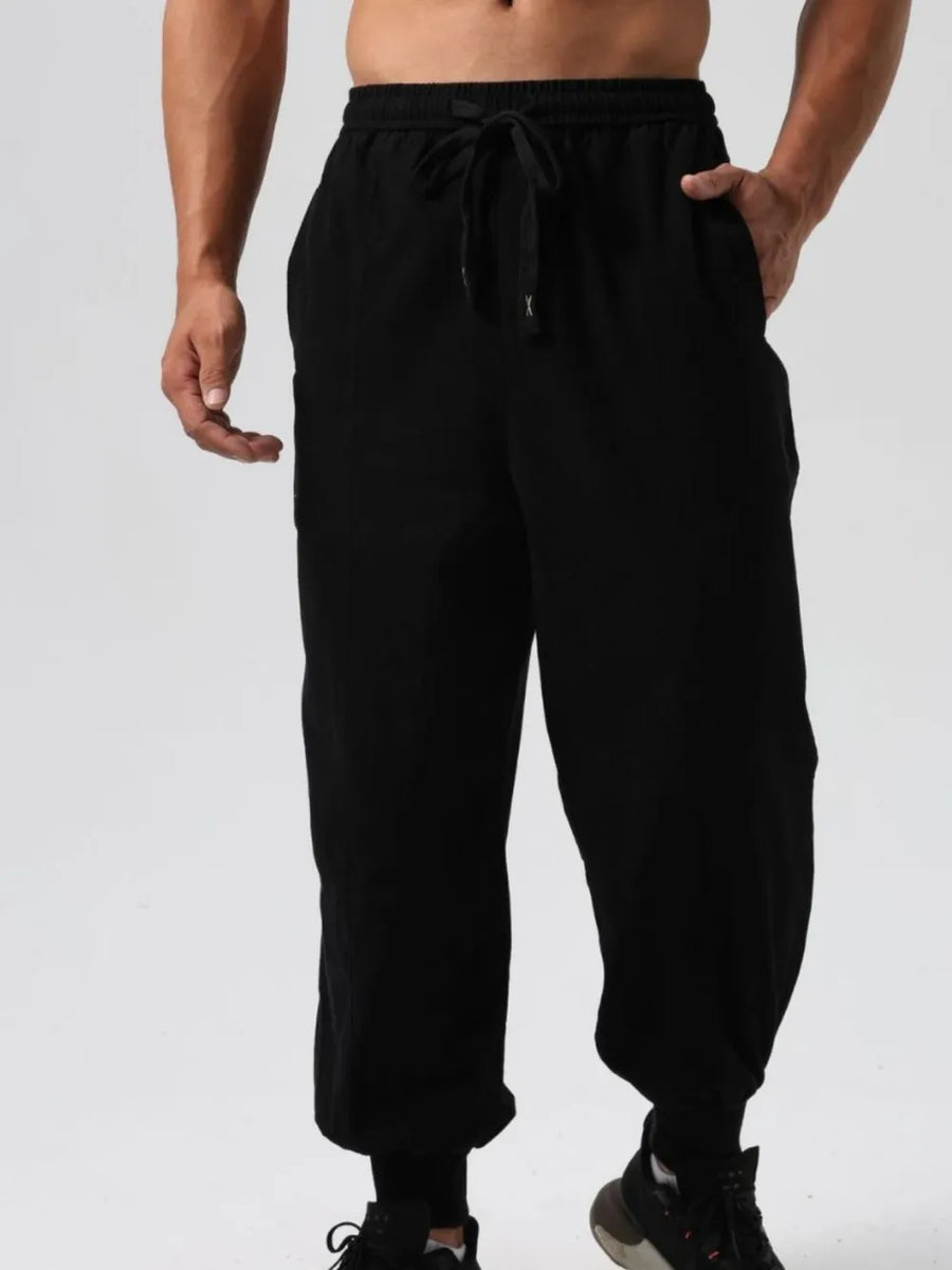 Black relaxed fit joggers with adjustable drawstring waist and seam details.