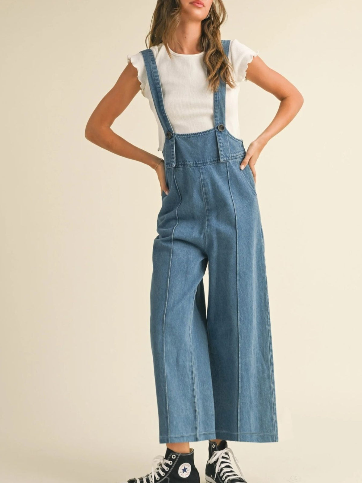 Denim wide leg overalls with adjustable straps and button details, styled with a white top.