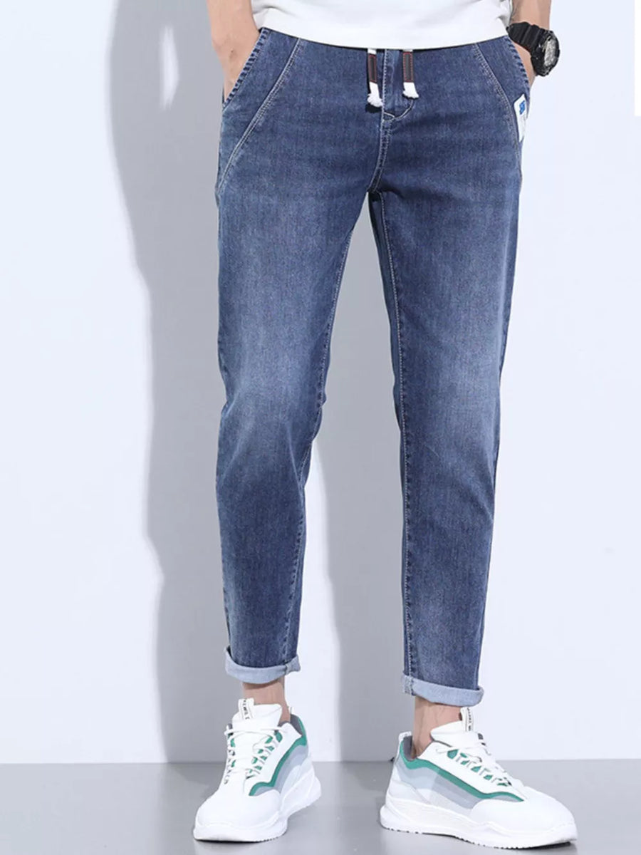 Washed skinny jeans in dark blue with adjustable drawstring and cuffed ankles.