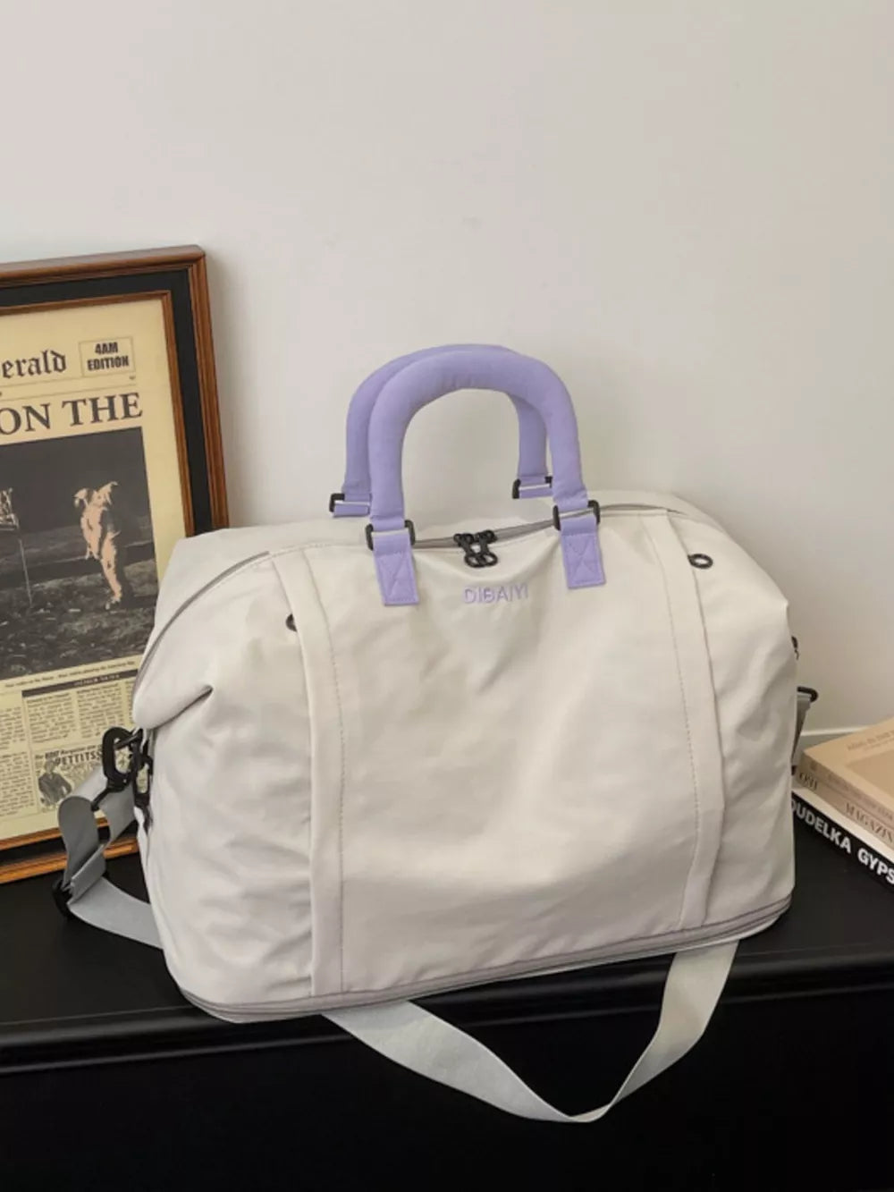 Sleek grey nylon travel bag with purple handles and adjustable shoulder strap.
