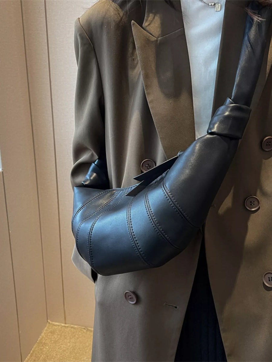 Black leather hobo bag with curved stitching detail and knotted strap.