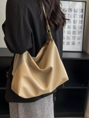 Sculptural PU leather shoulder bag in khaki with adjustable strap, worn with a black blazer.