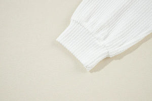 White ribbed knit sweatshirt cuff detail showing textured fabric and elasticized hem.