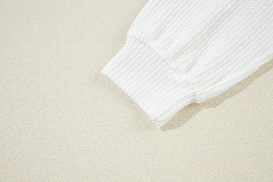 White ribbed knit sweatshirt cuff detail showing textured fabric and elasticized hem.