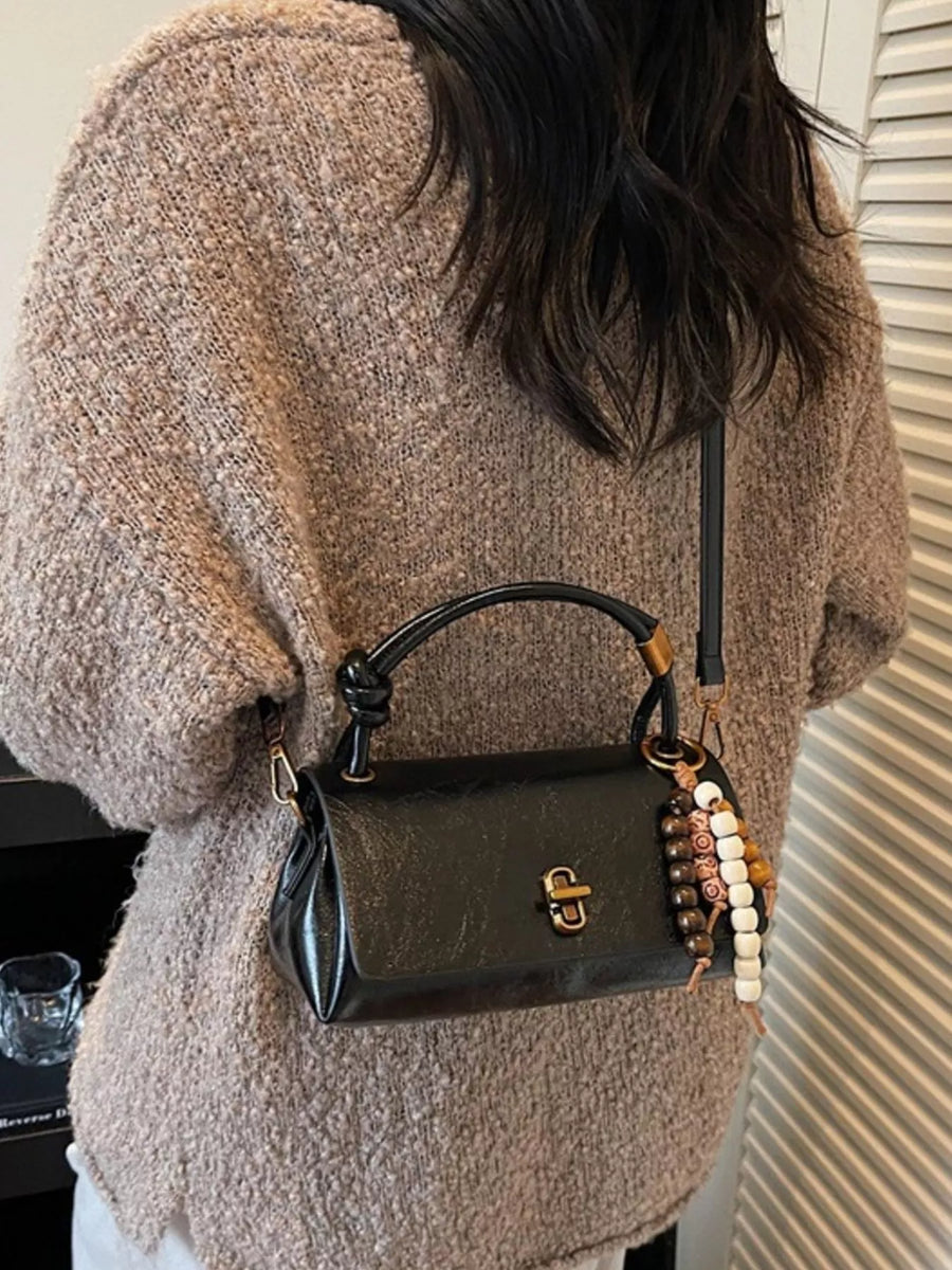 Black leather crossbody bag with bead charm and gold clasp