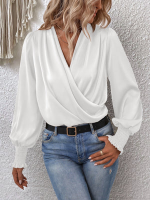 White ruched surplice blouse with long balloon sleeves and smocked cuffs.