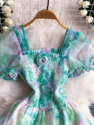 Floral midi dress with smocked bodice, sheer puff sleeves, and tie-dye print in green and pink.