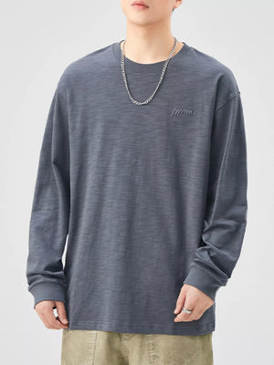 Oversized long-sleeve cotton tee in Space Gray with subtle embroidered logo detail.
