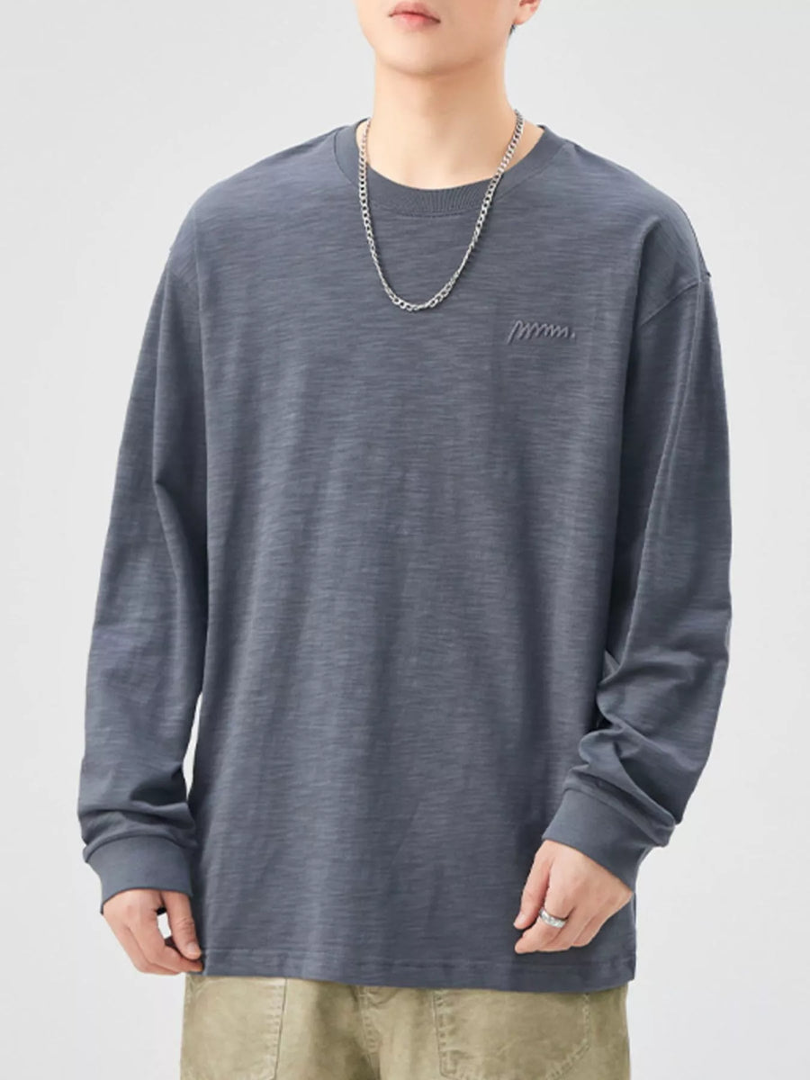 Oversized long-sleeve cotton tee in Space Gray with subtle embroidered logo detail.