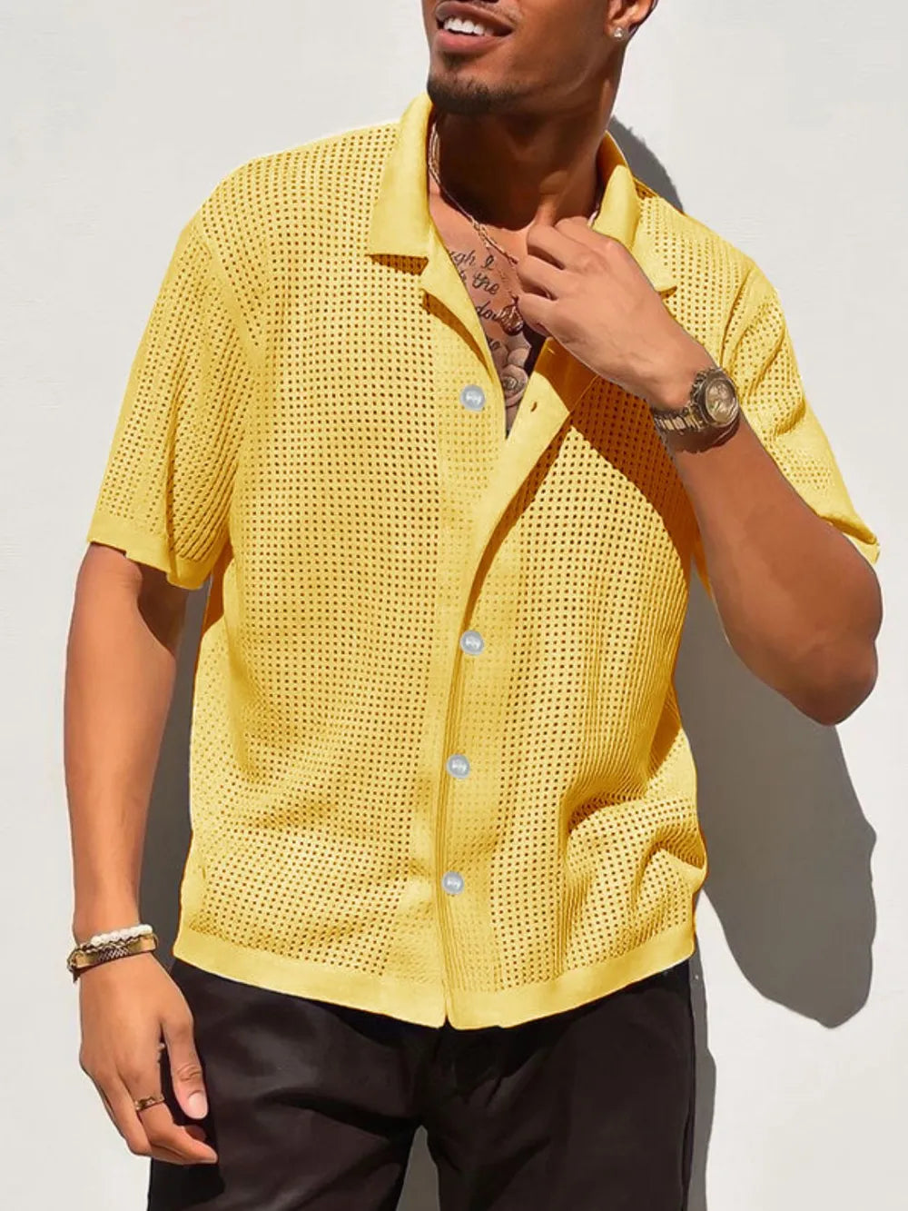 Yellow perforated knit resort shirt with short sleeves and a collared neckline.