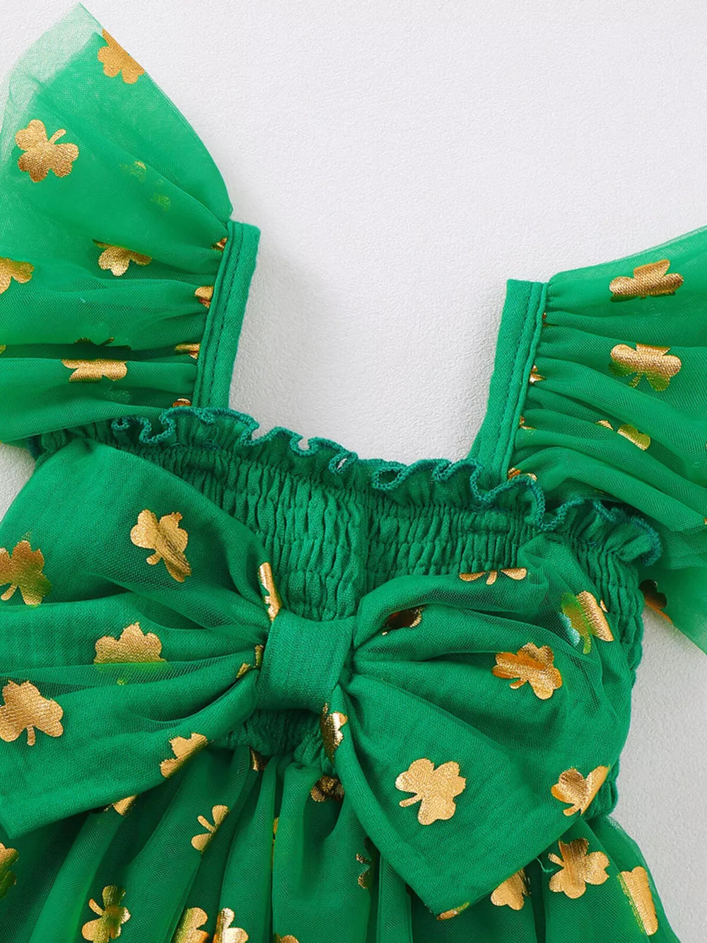 Green tulle baby dress with gold shamrock print, smocked bodice, and large front bow.