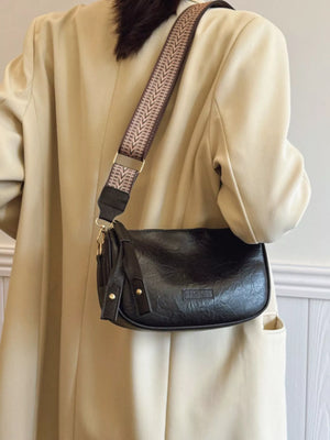 Black crossbody bag with textured faux leather and patterned strap