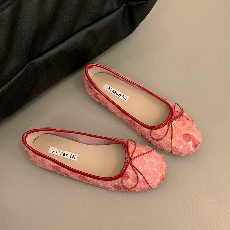 Pink floral bow slip-on flats with red trim and 3D texture.