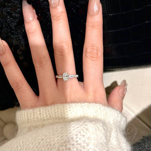 Sterling silver oval moissanite ring with diamond band detail.