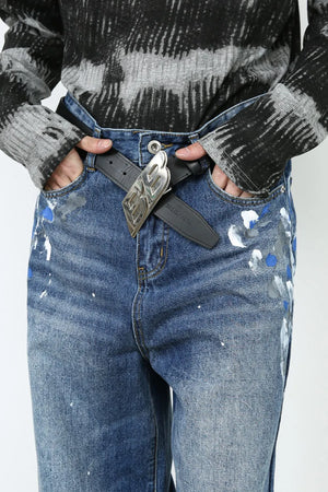 Painterly denim palazzo trousers in medium wash with artistic paint splatters and a statement buckle belt.