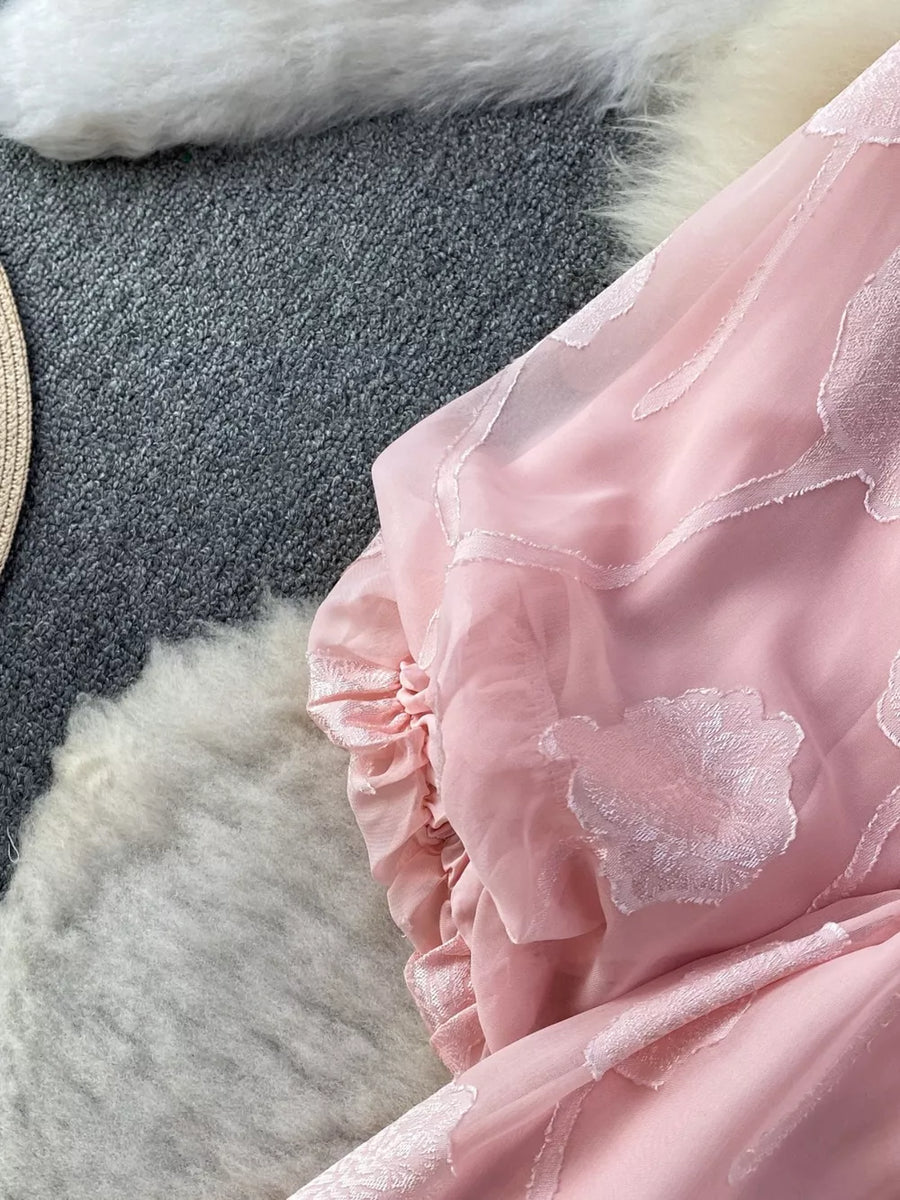 Pink chiffon maxi dress with floral embroidery and ruffled sleeve detail.