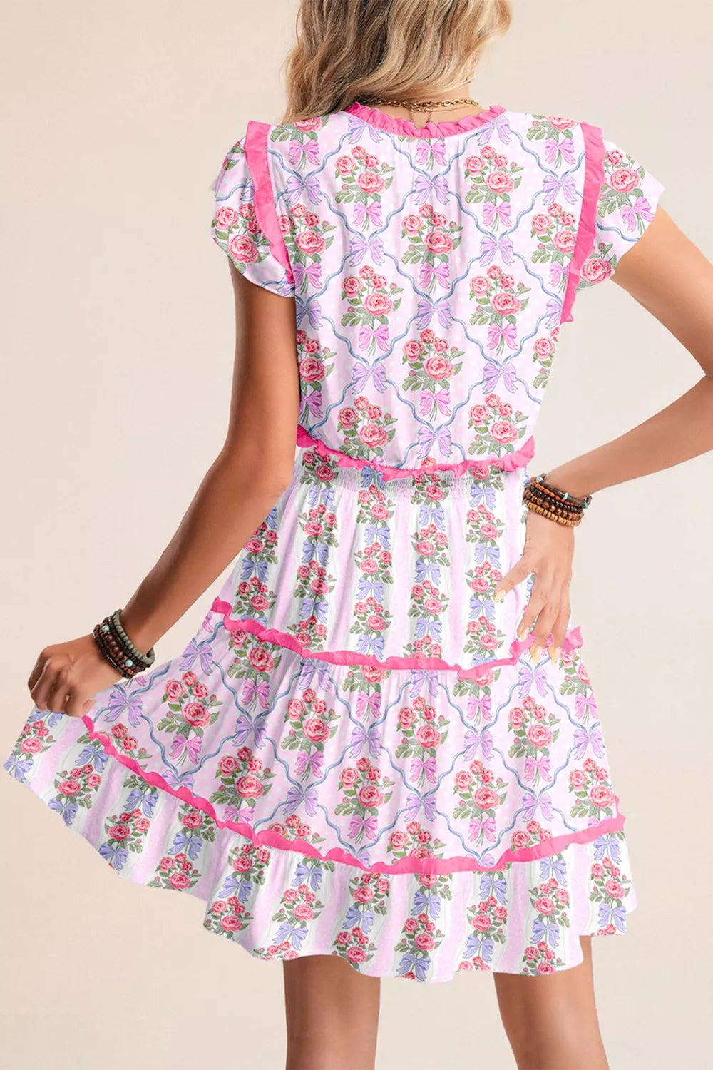 Floral tiered ruffle dress with bouquet and bow print, elastic waist, and pink trim.