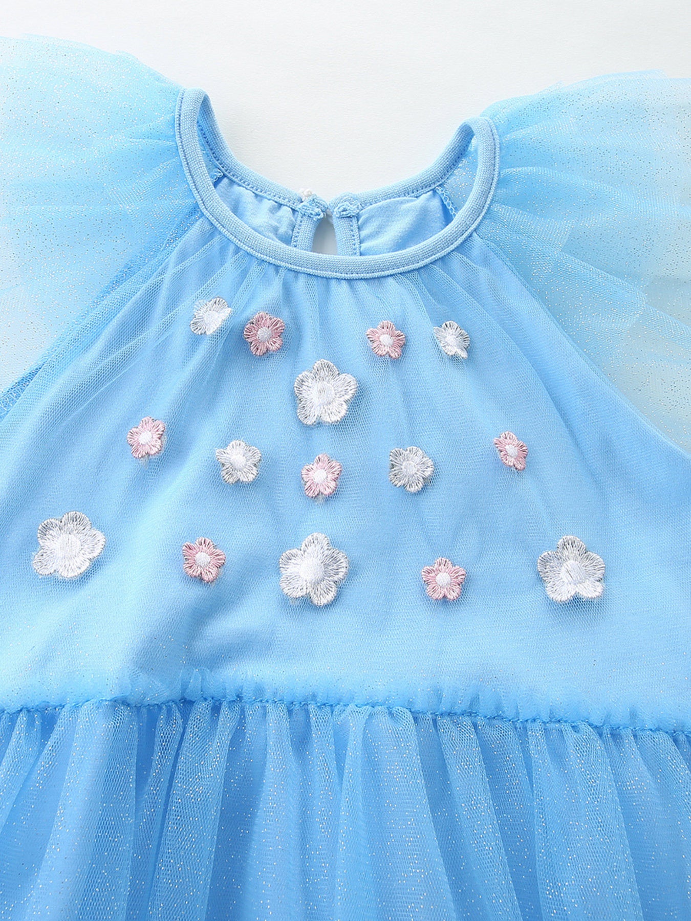 Blue tulle baby dress with cap sleeves and floral embroidery detail.