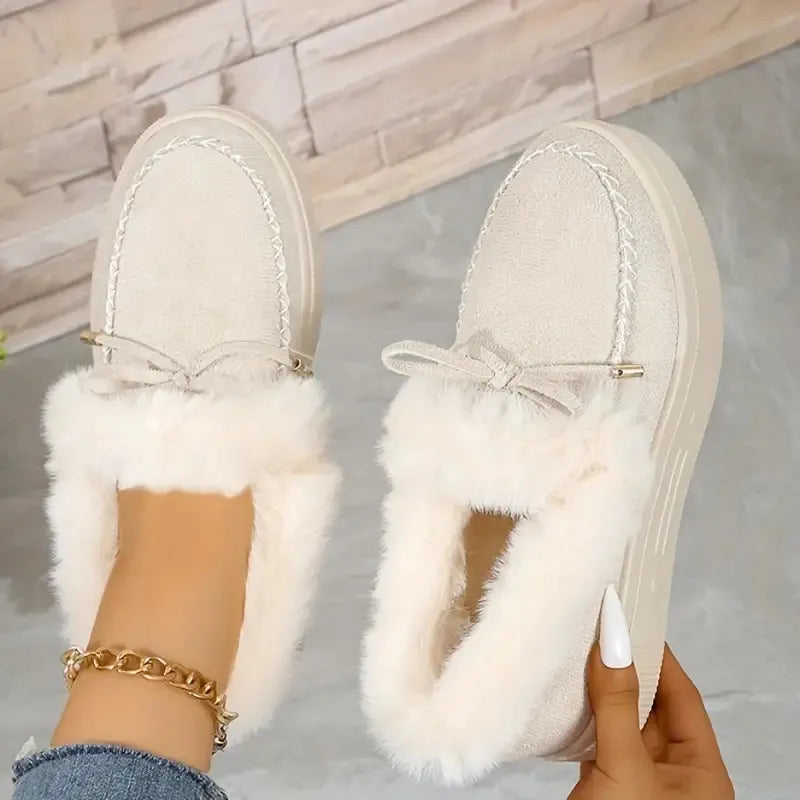Beige suede loafers with shearling trim and bow detail.