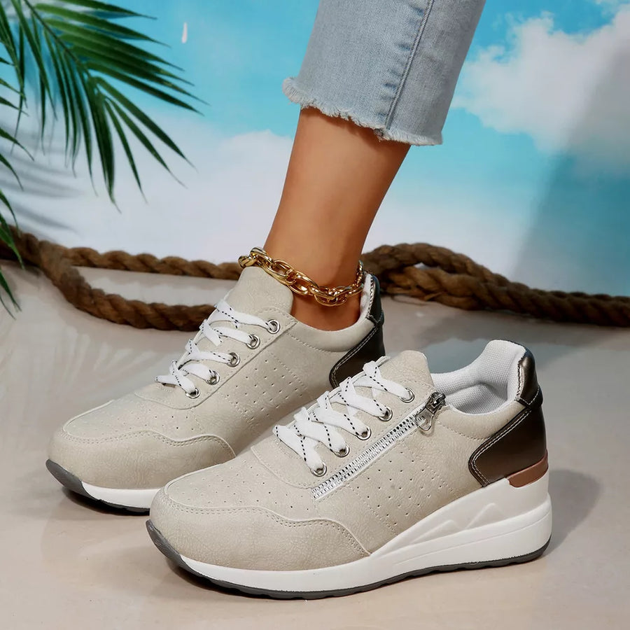 Beige lace-up wedge sneakers with side zipper detail and metallic heel accent.