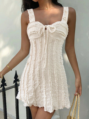 Beige ruched sweetheart neck mini dress with tie detail and textured fabric.