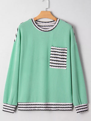 Turquoise long-sleeve top with twisted ribbed texture, a striped pocket, and striped cuffs.
