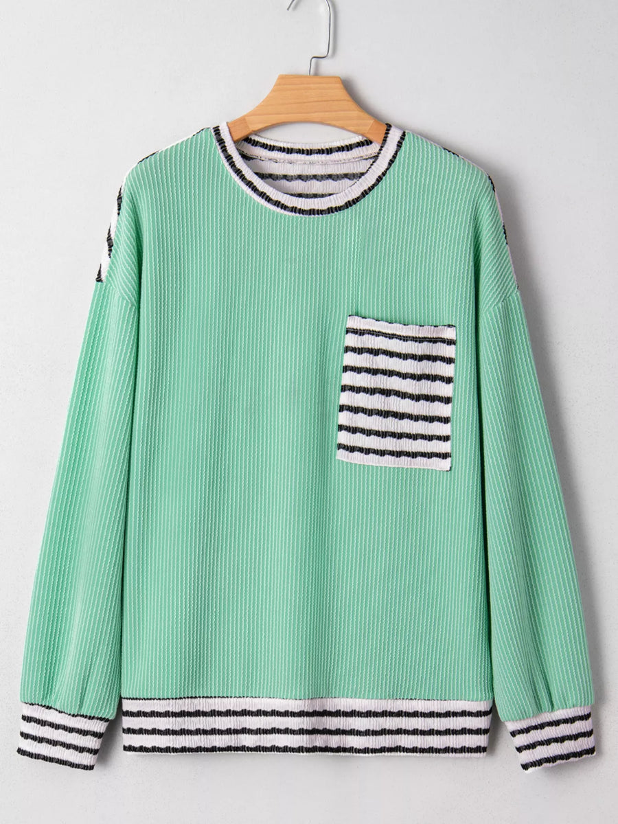 Turquoise long-sleeve top with twisted ribbed texture, a striped pocket, and striped cuffs.