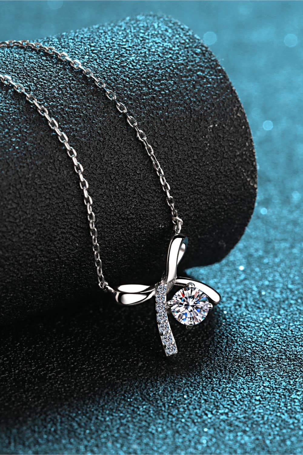 Silver bow-tie diamond pendant necklace with a clear round-cut diamond and pave accents.
