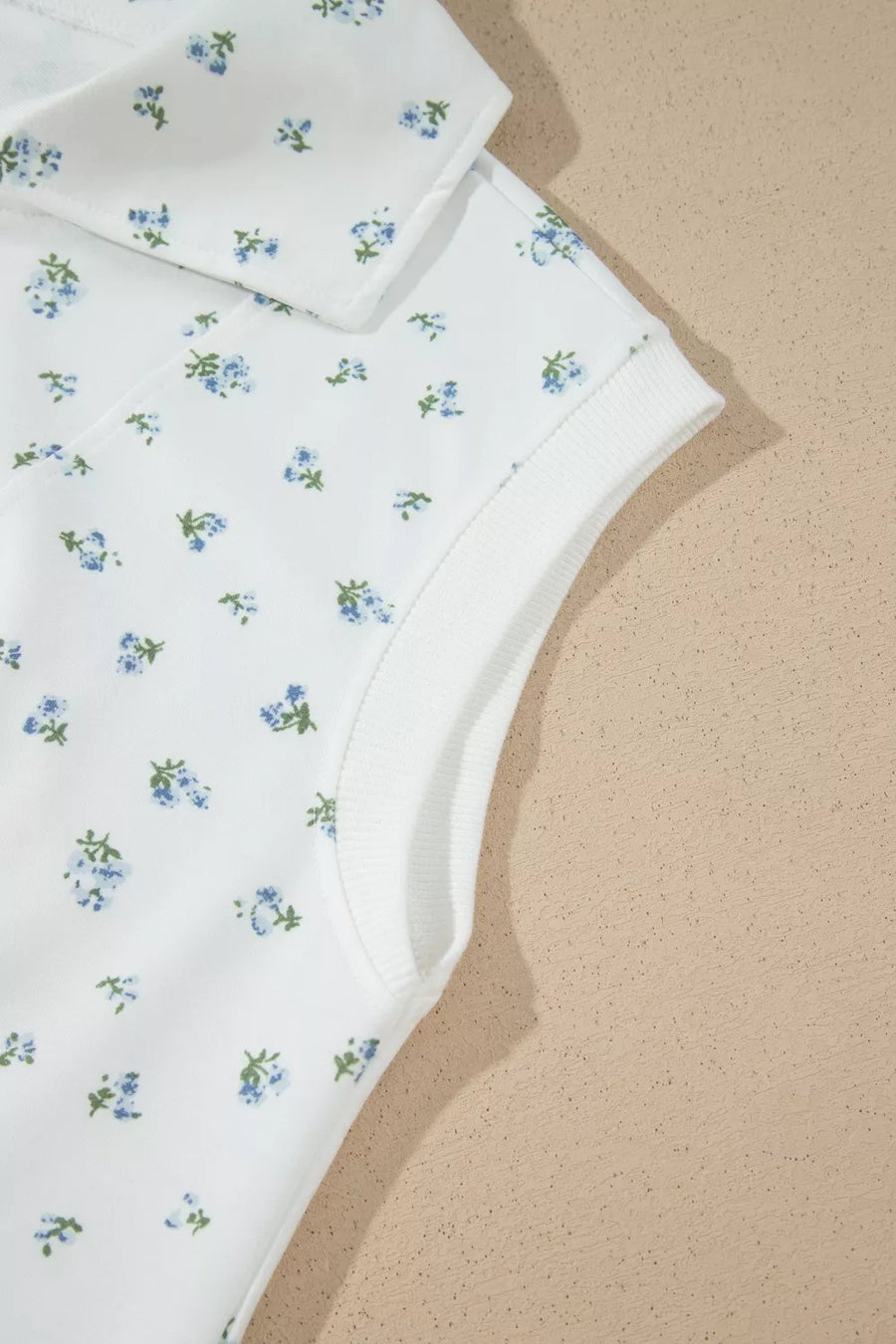 White sleeveless top with blue floral print and ribbed neckline