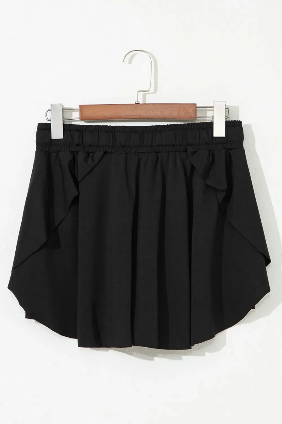 Black flared skort with tie waist and ruffled hem detail.