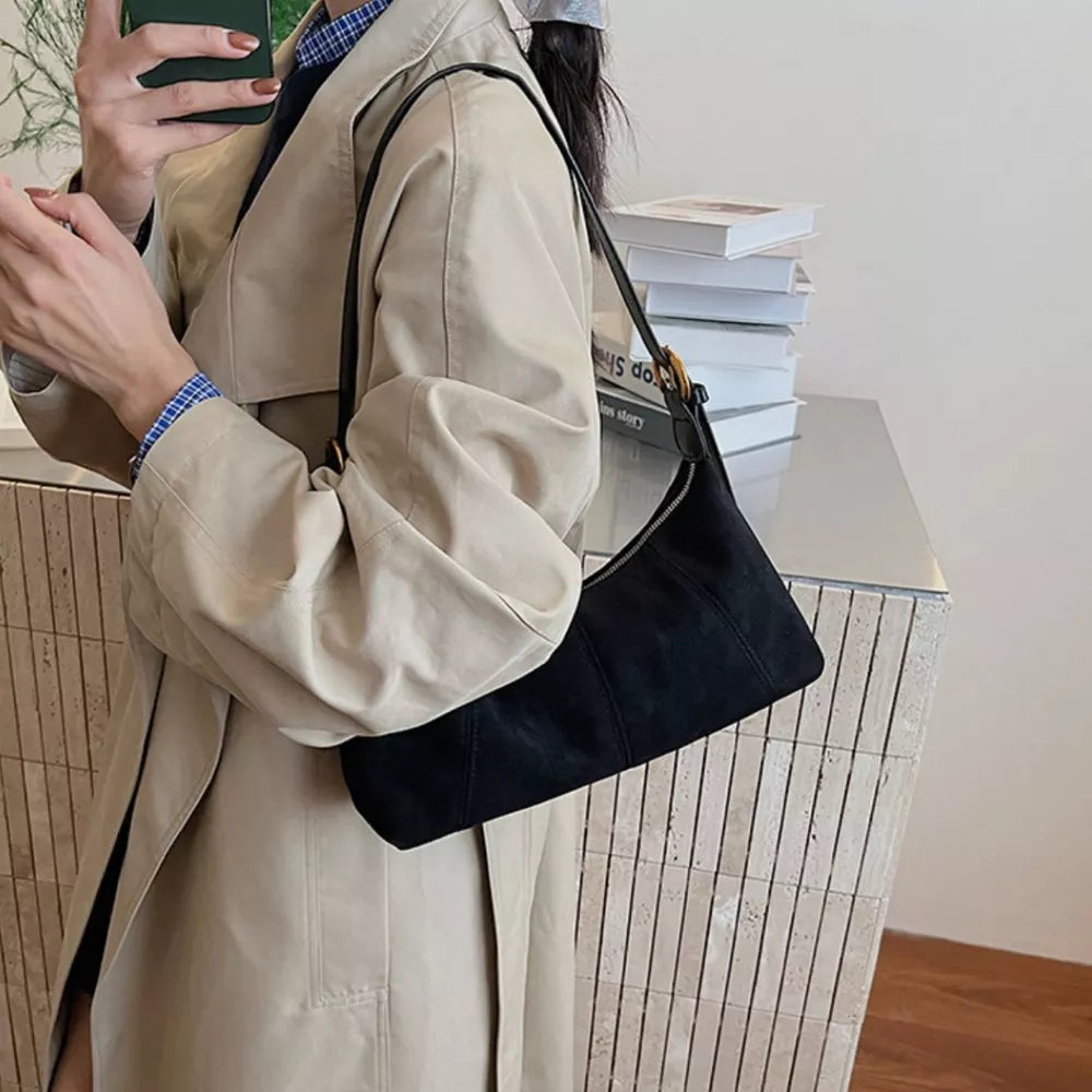 Black suede crescent shoulder bag with adjustable strap and zip closure.