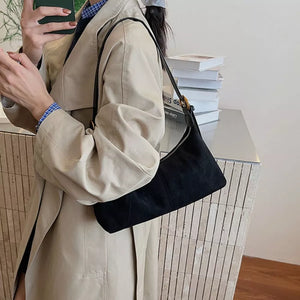 Black suede crescent shoulder bag with adjustable strap and zip closure.