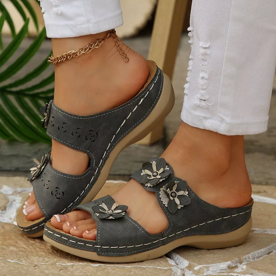 Gray floral appliqué sandals with cutouts and white stitching.