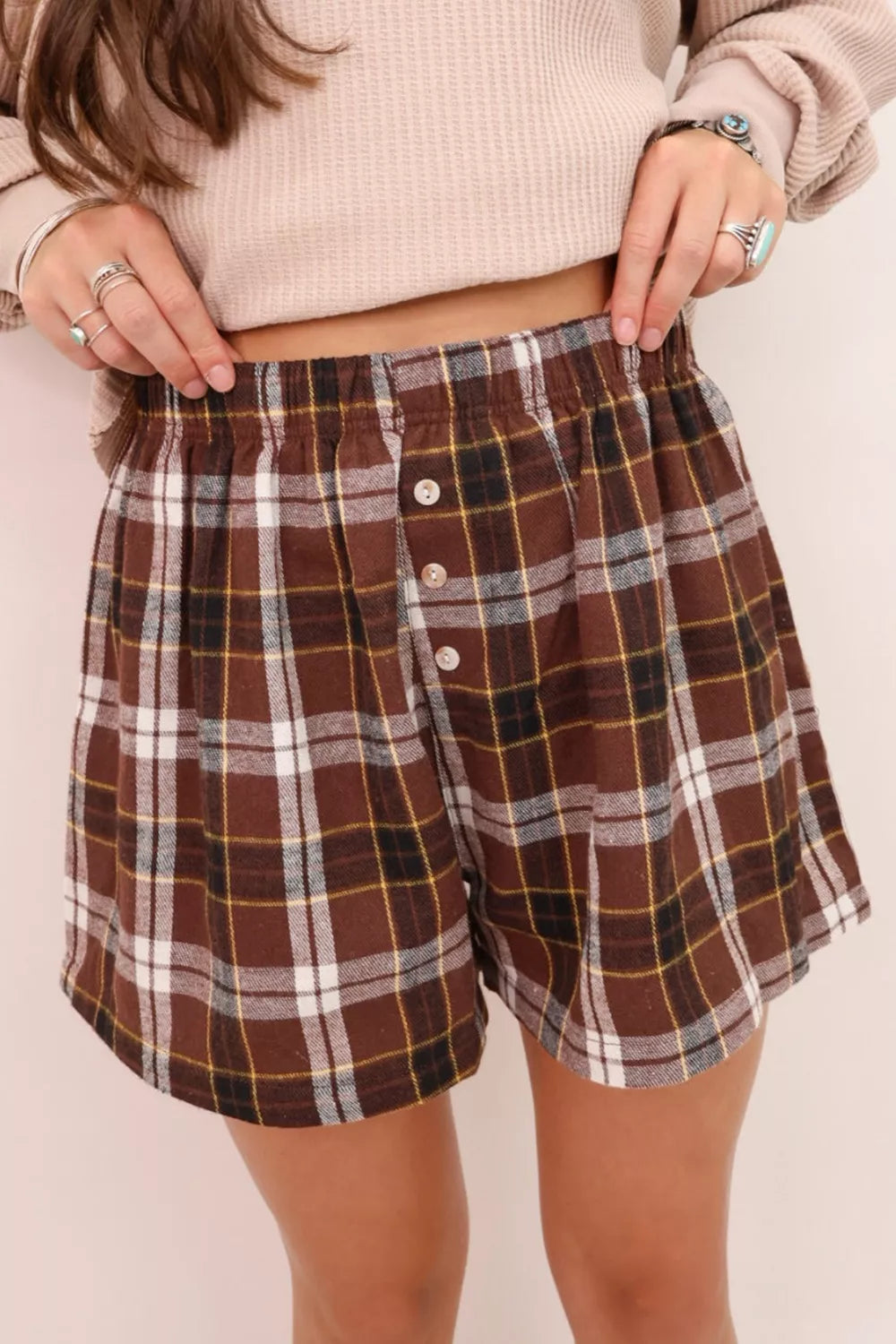 Brown plaid cotton shorts with elastic waist and button details.