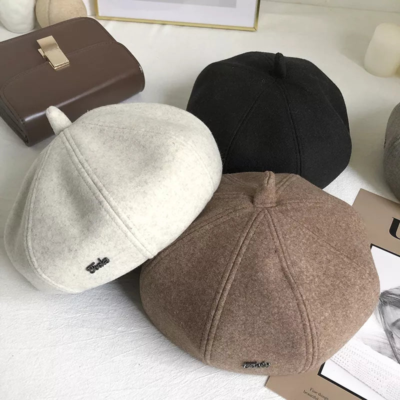 Woolen beret with paneled design in ivory, black, and beige, featuring a small embroidered logo detail.