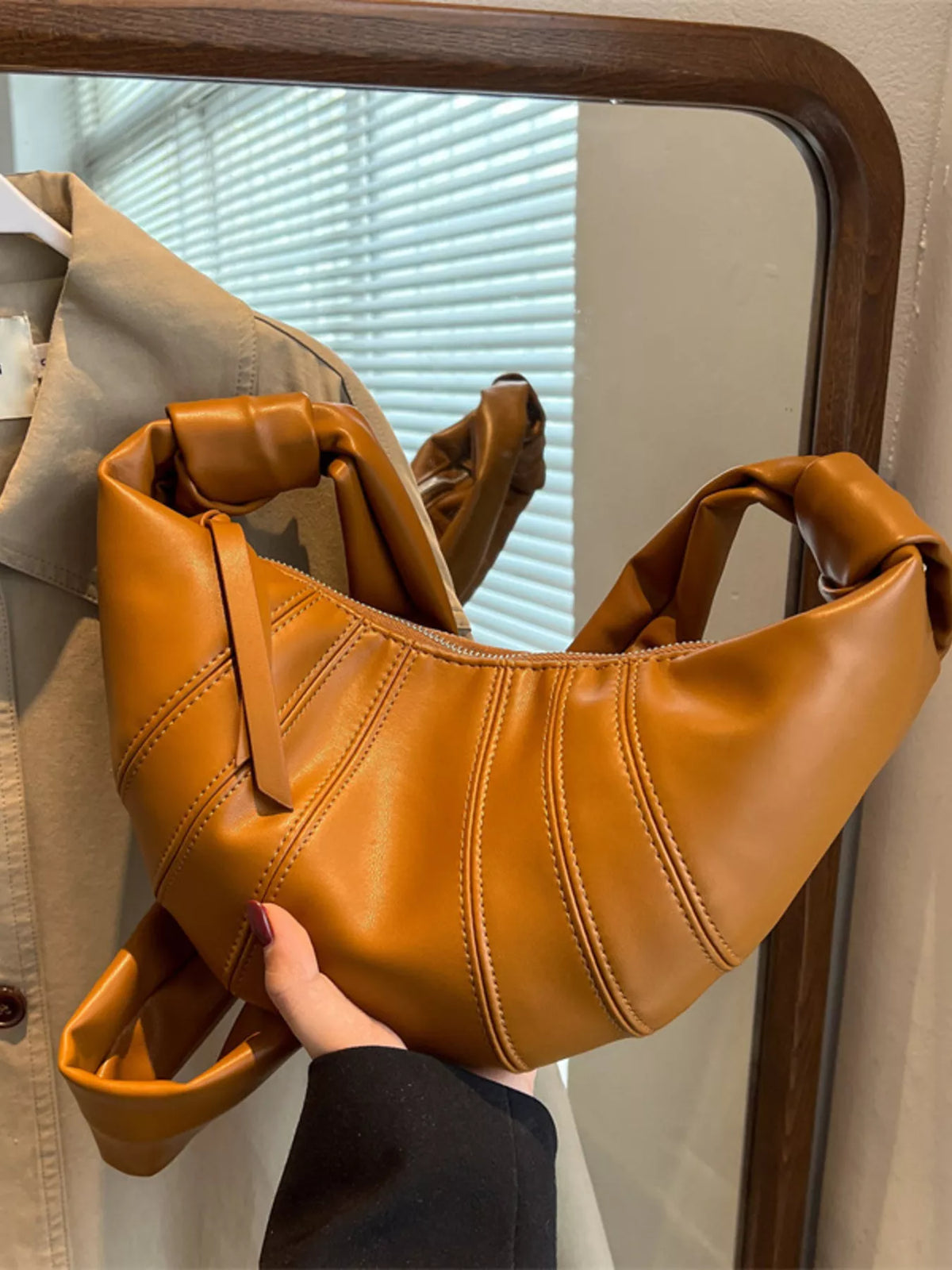 Chic crescent hobo crossbody bag in brown with stitched detailing and a knotted strap.