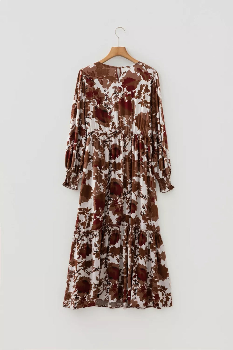 Maxi dress with brown and beige floral print, billowy sleeves, and tiered skirt.
