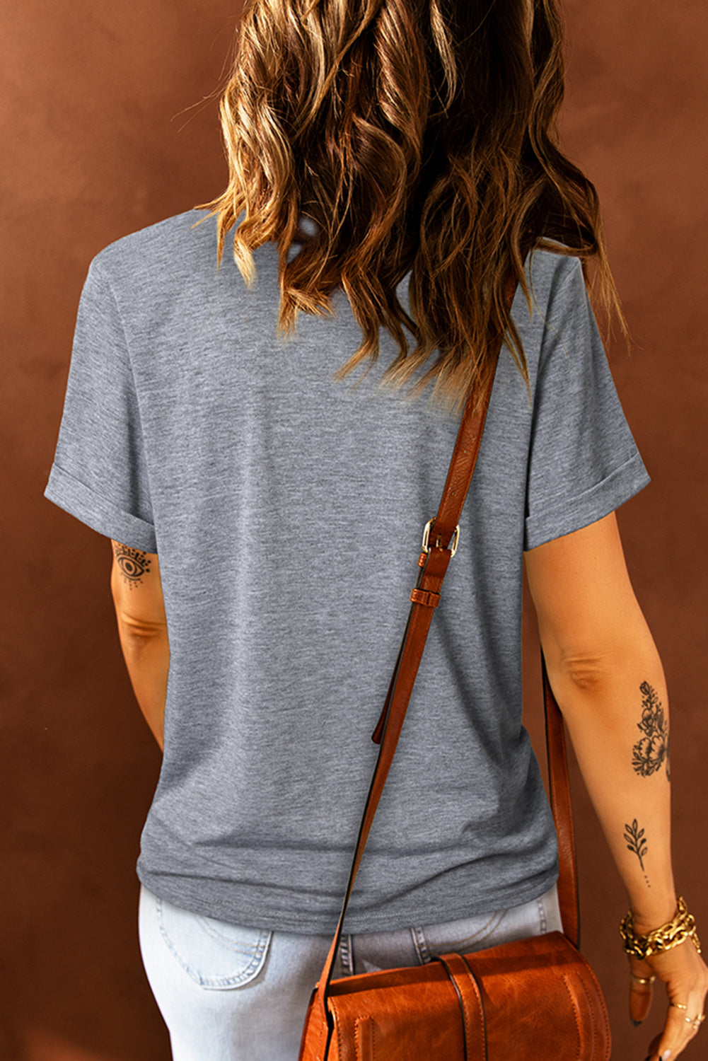 Mid gray basic t-shirt with short rolled sleeves and a crew neck, worn with jeans.