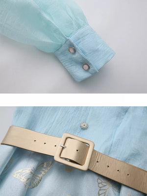 Light blue midi dress with butterfly print, cinched waist belt, and buttoned cuff detail.