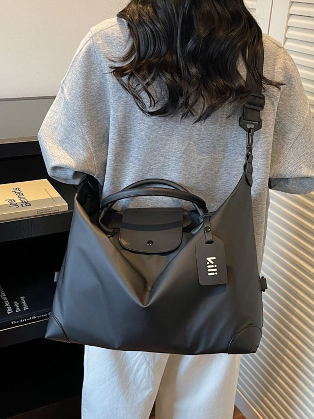 Black minimalist large travel duffel bag with detachable strap and luggage tag.