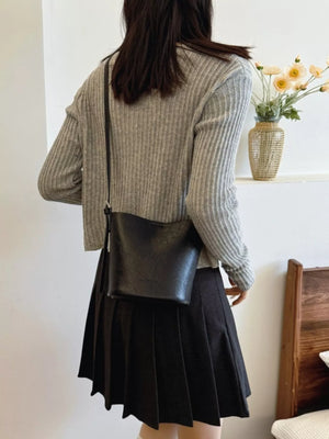 Black leather bucket crossbody bag with a simple design and adjustable strap.