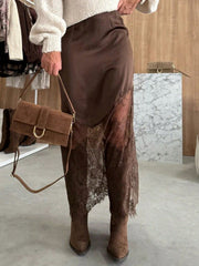 Brown satin skirt with asymmetrical lace trim and body-skimming fit.
