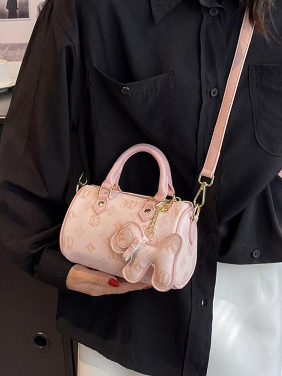 Pink mini barrel crossbody bag with allover logo pattern and elephant charm