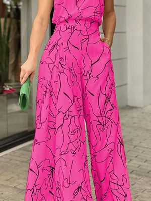 Hot pink halter neck romper with abstract face print and wide legs.