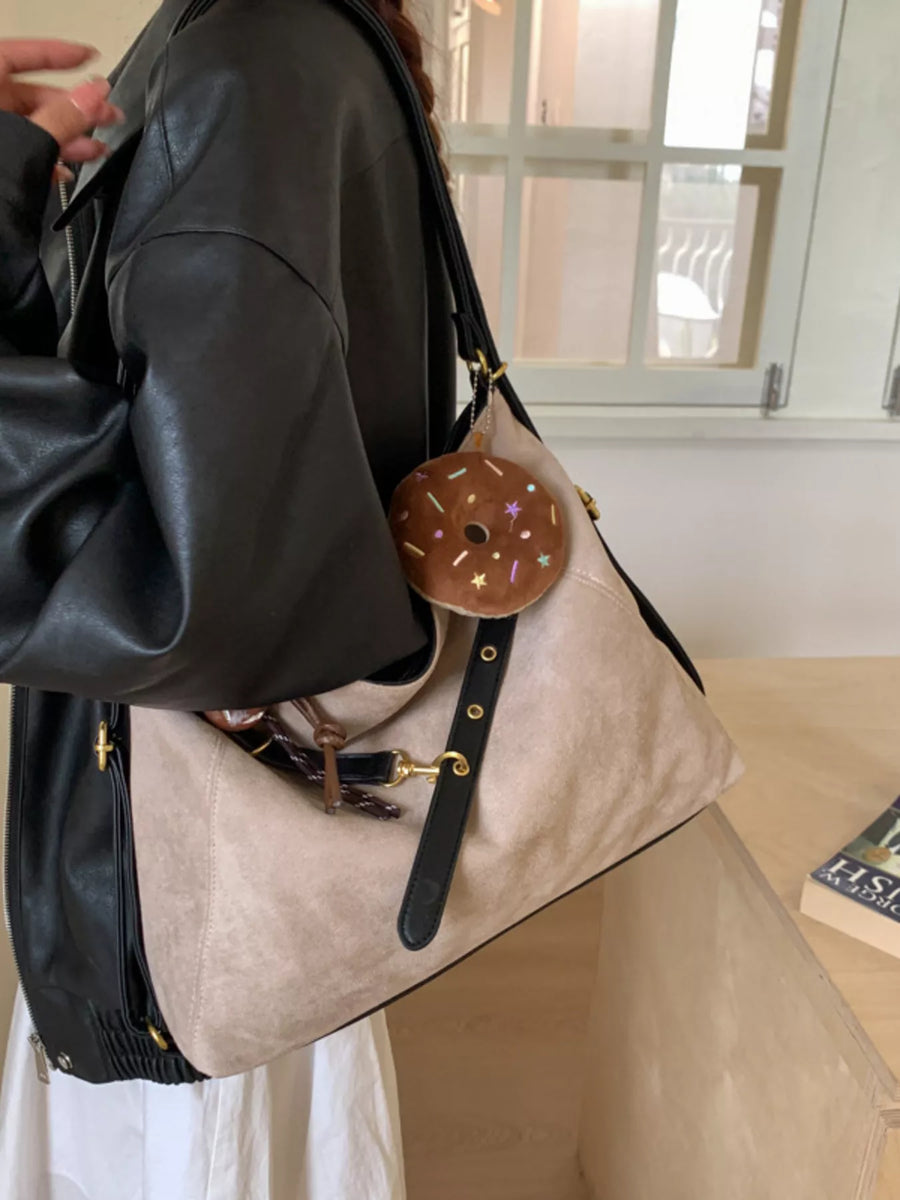 Chic hobo bag in khaki with adjustable strap and donut charm accessory.