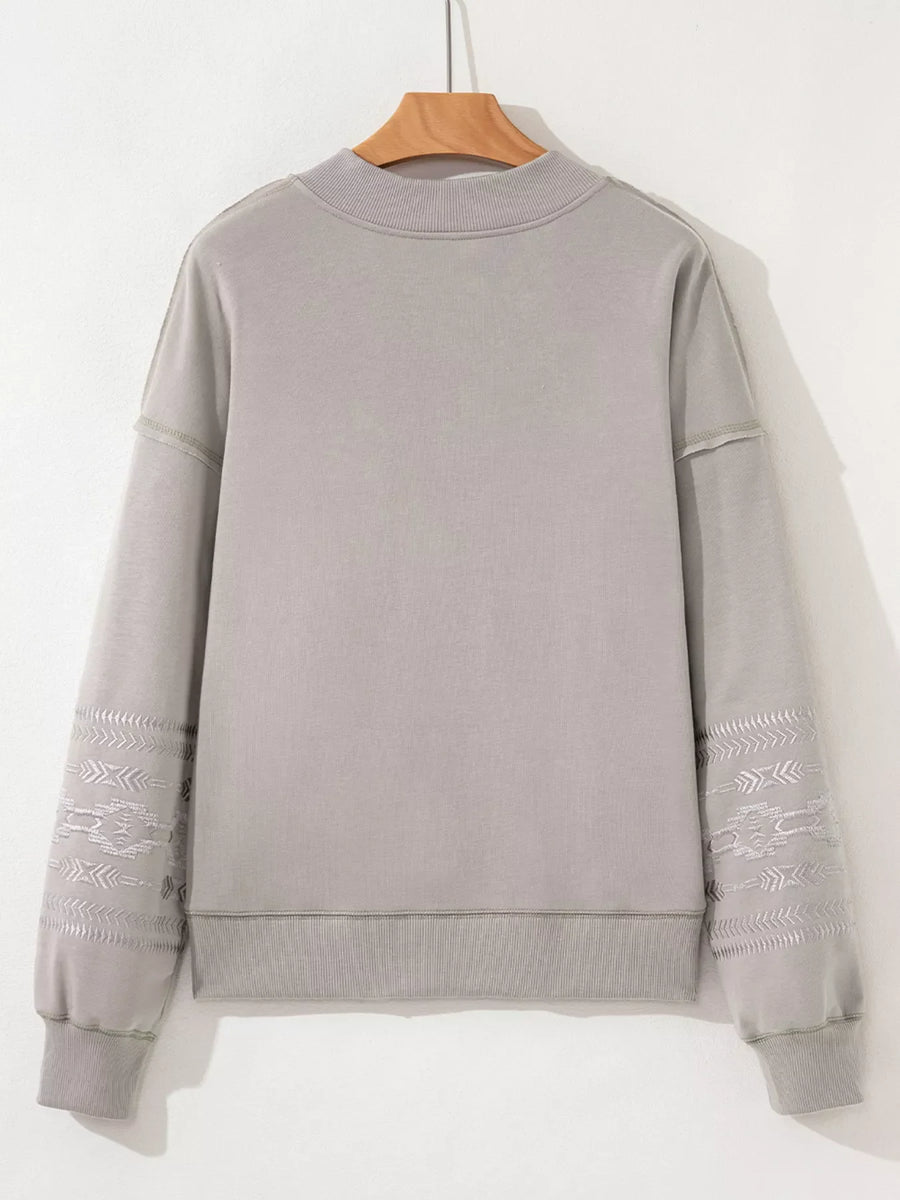 Gray sweatshirt with Aztec embroidery on sleeves and crew neck.