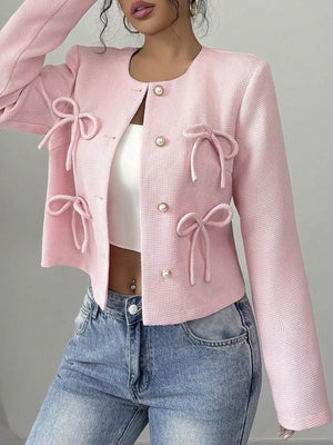 Pink textured jacket with pearl buttons and bow details, crew neck, long sleeves.
